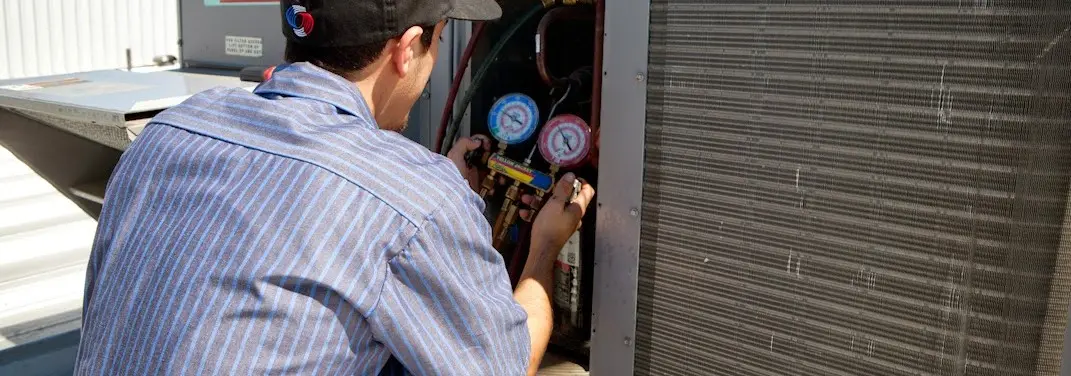 HVAC technician servicing a condenser unit in Mead Valley